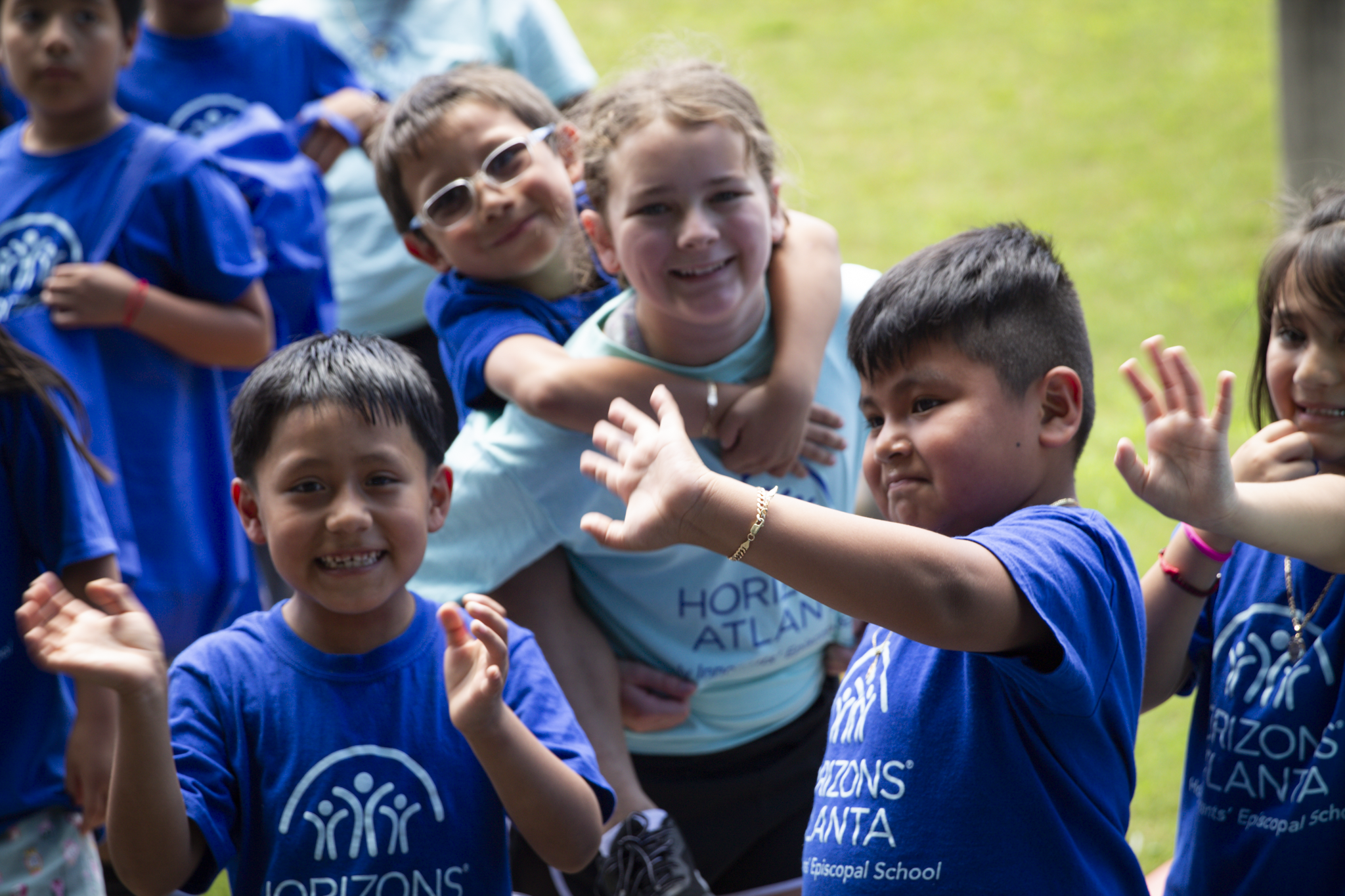 Image: Young children wearing Horizons Atlanta summer shirts from their different sites laughing and playing a game with their hands outside.
