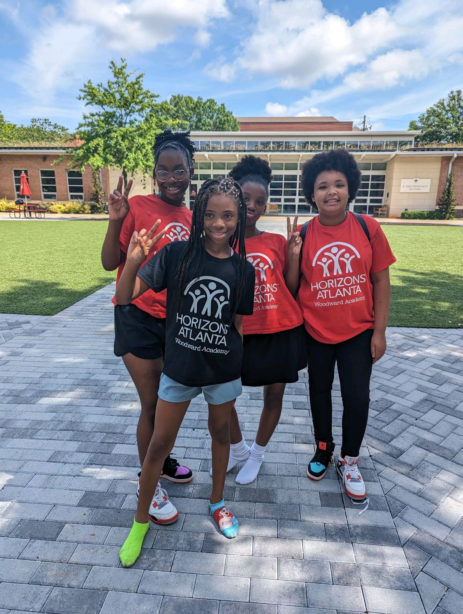 Young girls from Horizons Atlanta's Woodward Academy summer learning program posing in front of an arts building